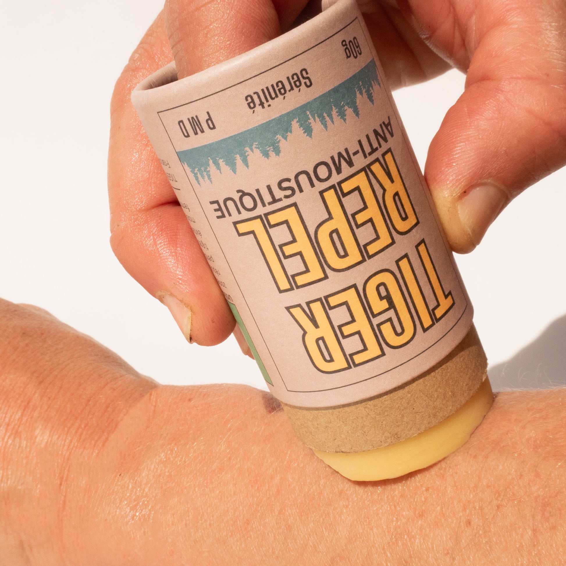  Gros plan sur une main appliquant le baume anti-moustique solide TigerRepel sur la peau. Formulé avec Citriodiol et des ingrédients naturels, ce répulsif protège efficacement contre les moustiques, y compris le moustique tigre. Format stick pratique et biodégradable, idéal pour une application facile.